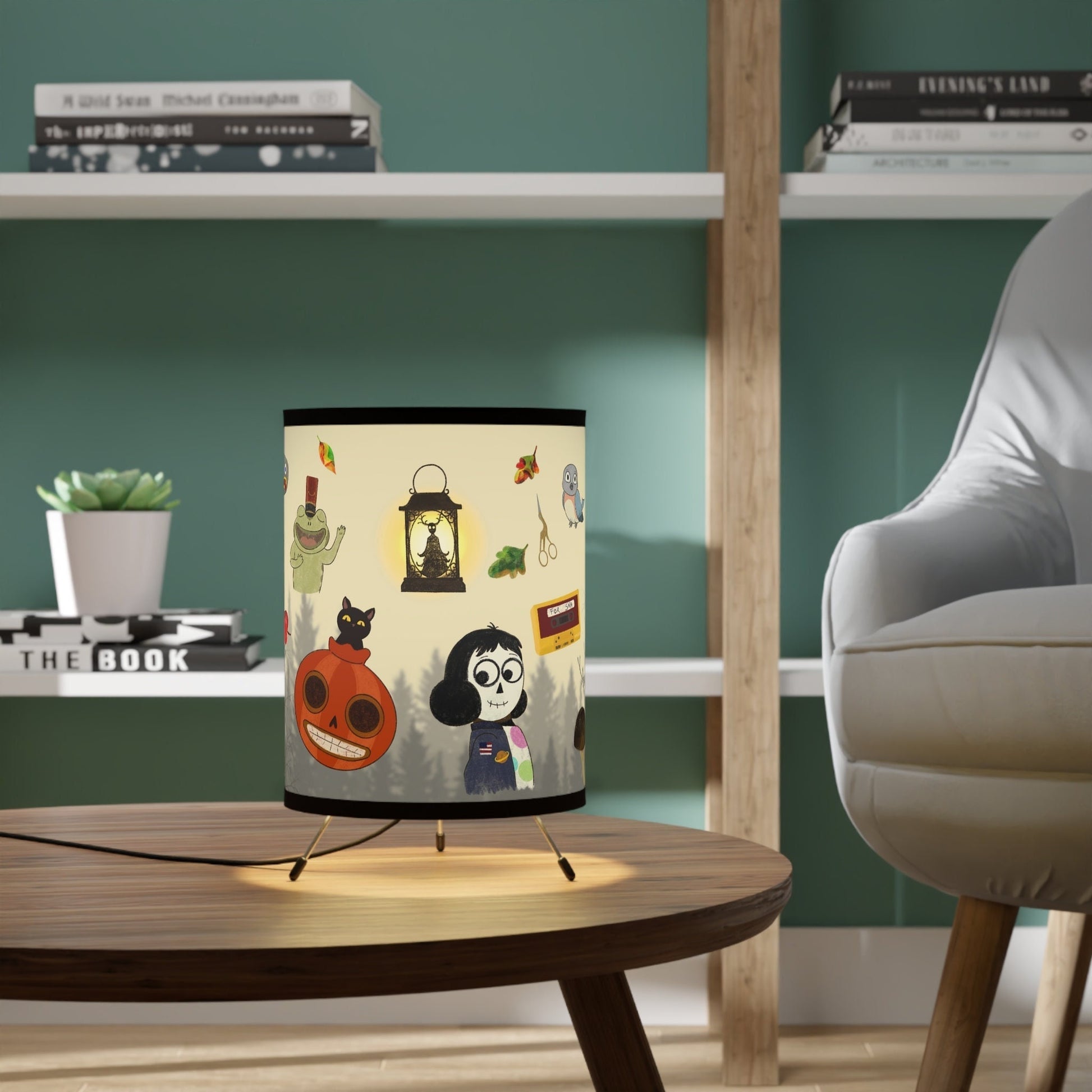 A decorative lamp featuring an Over the Garden Wall themed lampshade with images of Wirt, Greg, Jason Funderburker and more, sits on a table in a stylish living room.