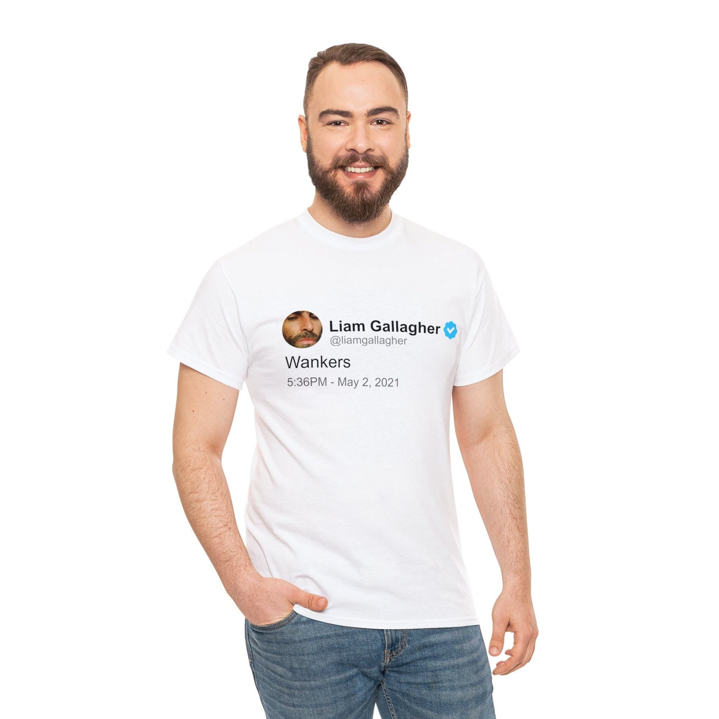 A smiling man models a white T-shirt adorned with a humorous tweet from Liam Gallagher in black text. The shirt highlights Liam's distinctive wit, offering a blend of rock 'n' roll attitude and playful humor.